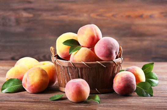Fresh peaches in wicker basket on wooden background