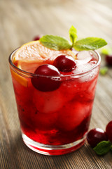 Glass of cherry juice on wooden table, closeup