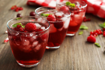 Glasses of berry juice on wooden table, closeup