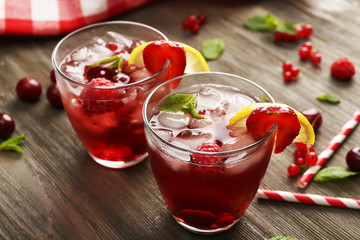 Glasses of berry juice on wooden table, closeup