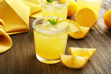 Glasses of lemon juice on wooden table, closeup