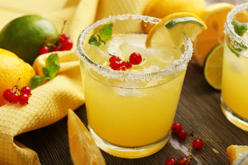 Glass of lemon juice with red currants on wooden table, closeup