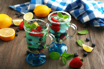 Glasses of berries juice on wooden table, closeup