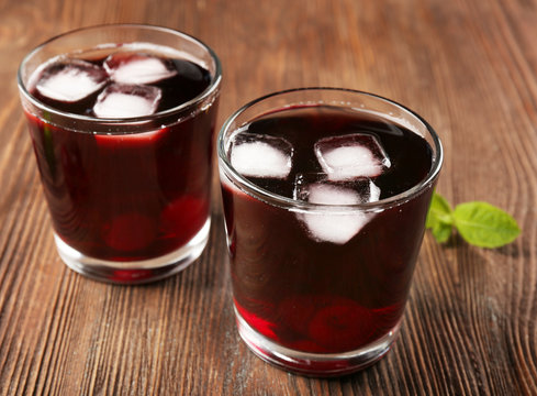 Glasses of cherry juice on wooden background