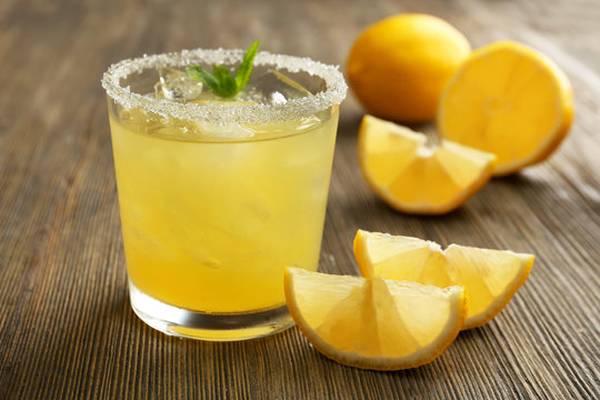 Glass of lemon juice on wooden table, closeup