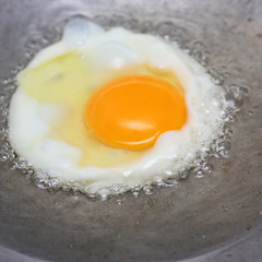 cooking fried egg in hot pan with oil