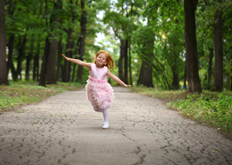 Happy little girl runs in a summer park