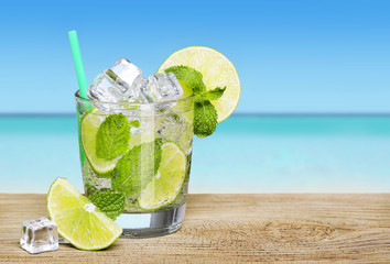 Mojito cocktail with lime over tropical beach background