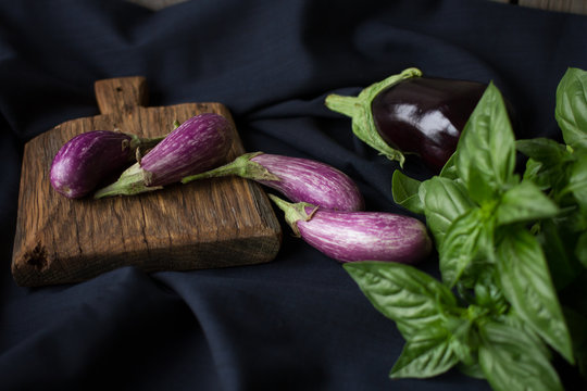 small eggplant with basil on a black background