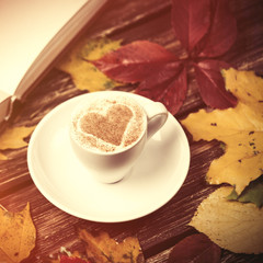 Autumn leafs, book and coffee cup on wooden table.