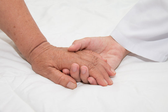 Doctor holding an old woman's hand