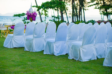 Rows of white covered chairs for asian buddhist wedding ceremony