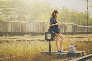 Beautiful girl playing to mobile at railway station.