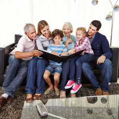 Familie schaut Fotobuch an im Wohnzimmer