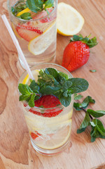 homemade lemonade with mint and strawberries on a wooden