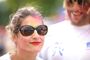 Attractive woman in sunglesses with painted face, celebration of holi festival