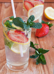 homemade lemonade with mint and strawberries on a wooden