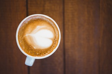 Cup of cappuccino with coffee art on wooden table