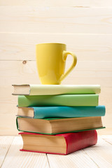 Fototapeta na wymiar Stack of colorful books and cup on wooden table. Back to school. Copy space