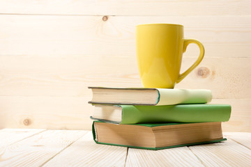 Stack of colorful books and cup on wooden table. Back to school. Copy space