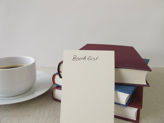 Book pile, blank booklist and cup of coffee