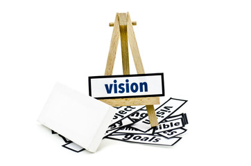 concept vision word on wooden stand.random cutted print paper and empty canvas frame isolated white background