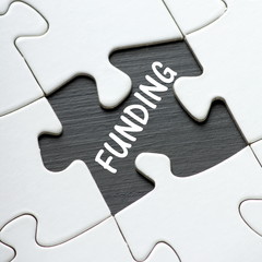 The word Funding in white text on a blackboard as revealed by a missing jigsaw puzzle piece