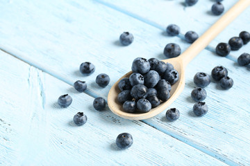 Blueberries in spoon on a blue wooden background