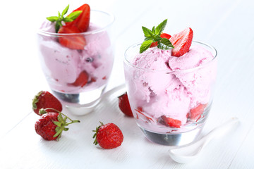Ice cream in glasses with strawberries on white wooden backgroun