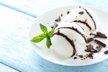 Sweet ice cream in plate on blue wooden background
