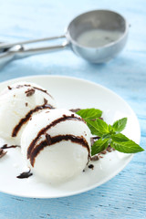 Sweet ice cream in plate on blue wooden background