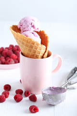 Waffle cone with raspberries and ice cream on wooden table