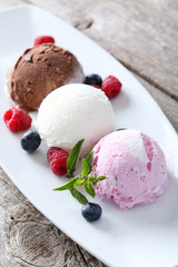 Ice cream on plate with berries on grey wooden background