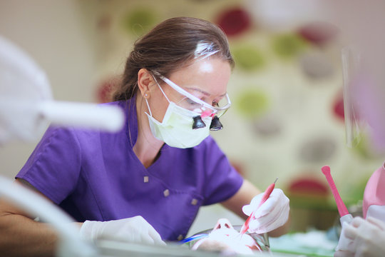 Dentist Wearing Surgical Loupes Treating Patient's Teeth