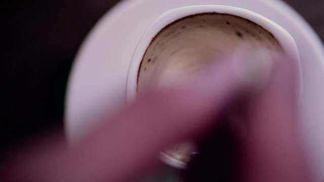 human hand taking mix coffee in white cup with spoon