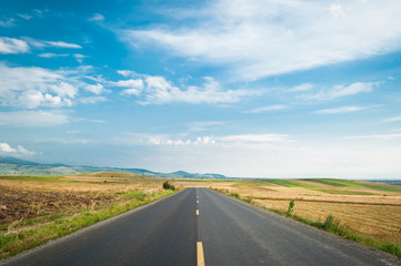 An open road on a field, under the blue sky
