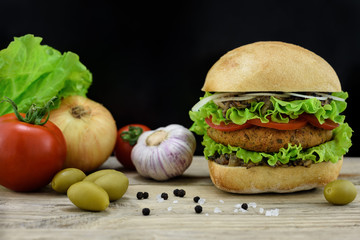 Burger with fresh vegetables on wooden desk