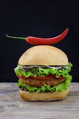 Burger with chili pepper on wooden desk
