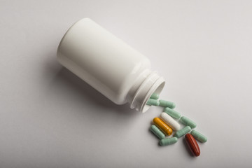 Colorful pills and pill bottle on white background