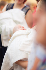 Mother hold baby on ceremony of child baptism