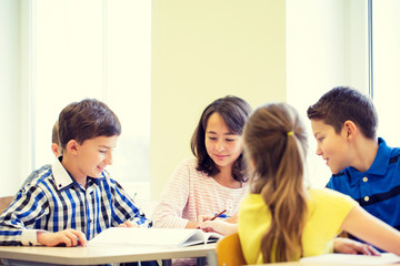 group of school kids writing test in classroom
