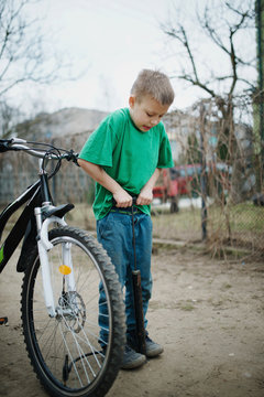 boy pumps up his bicycle wheel
