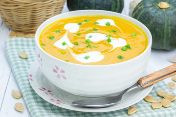 Pumpkin soup with sour cream on a wooden table