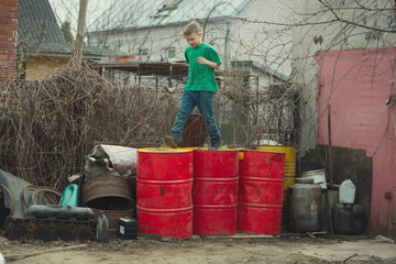 Fototapeta na wymiar boy walks on the barrels from oil