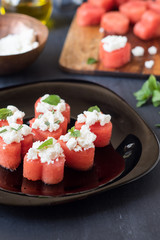Summer appetizer of heart-shaped watermelon with feta cheese and rosemary or mint leaves. Selective focus