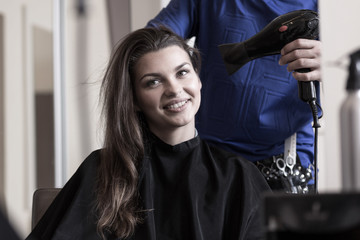 Fototapeta na wymiar Hairstylist drying woman's hair