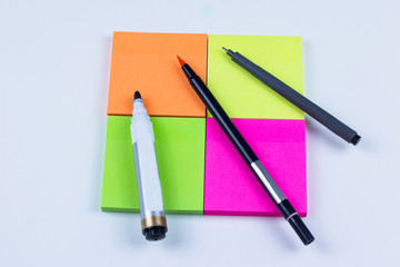 Square of colored sticky note with pens and markers