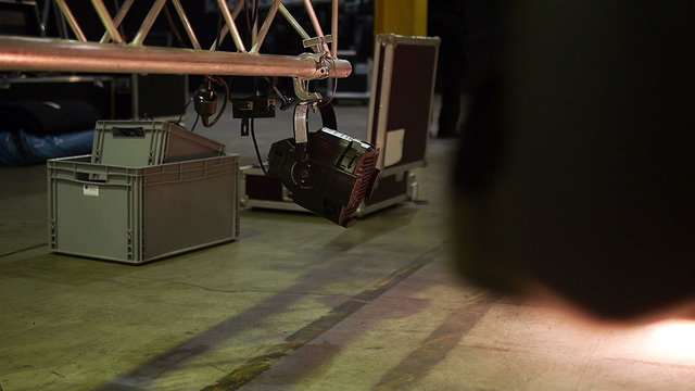 A spot light changing the modus during the stage construction in a hall and shining on a stage frame with spot light.