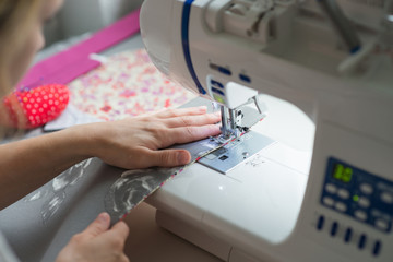 close woman hands sewing on sewing machine