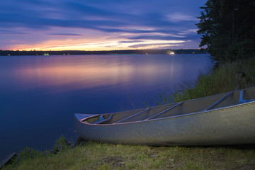 Canoe beached along north woods lake at dusk